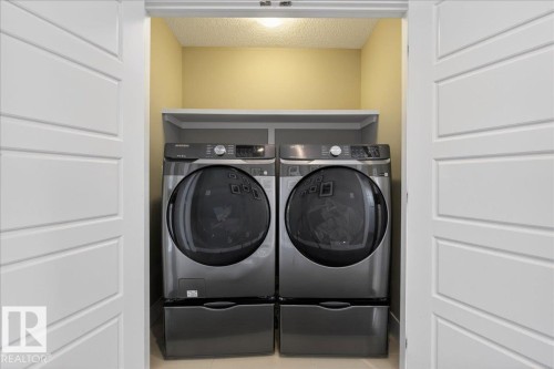 Dedicated laundry area featuring a washer and dryer, accompanied by an overhead shelf for storage - 606 Reynalds Way, Leduc, AB - Indoor Photo Showing Laundry Room