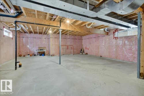 Spacious unfinished basement with exposed wood beams, overhead lighting, and insulated walls, offering significant potential for customization - 606 Reynalds Way, Leduc, AB - Indoor Photo Showing Basement