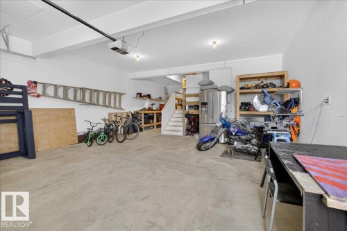 Spacious garage area featuring a concrete floor, white walls, and an overhead garage door opener - 606 Reynalds Way, Leduc, AB - Indoor Photo Showing Garage