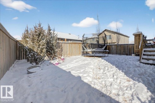 The property features a fenced yard with a deck and established evergreen trees - 606 Reynalds Way, Leduc, AB - Outdoor