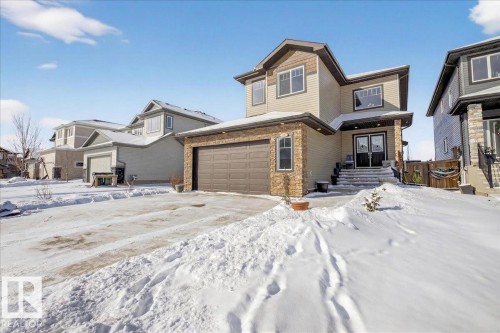 The property features a stone and siding exterior, a two-car garage, and a paved driveway - 606 Reynalds Way, Leduc, AB - Outdoor With Facade