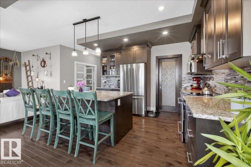 The property features a kitchen with dark cabinetry, granite countertops, and stainless steel appliances including a refrigerator - 606 Reynalds Way, Leduc, AB - Indoor