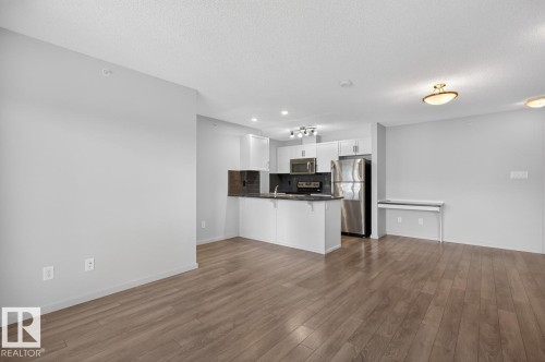 Open concept living space featuring wood-style flooring, light gray walls, and recessed lighting - 426 390 Windermere Road, Edmonton, AB - Indoor Photo Showing Kitchen