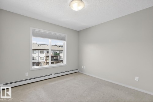 An inviting room featuring light-colored walls and carpeted flooring - 426 390 Windermere Road, Edmonton, AB - Indoor Photo Showing Other Room