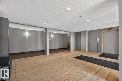 The property features a spacious common area with tile flooring and recessed lighting, accented by wall-mounted sconces - 426 390 Windermere Road, Edmonton, AB - Indoor Photo Showing Other Room