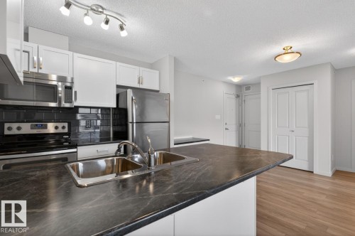 The kitchen features stainless steel appliances, including a microwave, oven, and refrigerator - 426 390 Windermere Road, Edmonton, AB - Indoor Photo Showing Kitchen With Stainless Steel Kitchen With Double Sink