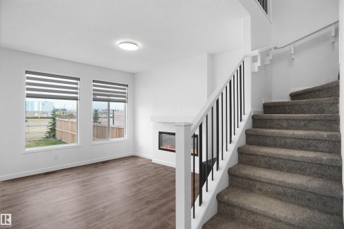 The living area features two large windows with blinds, a modern fireplace, and hardwood style flooring - Edmonton, AB - Indoor Photo Showing Other Room