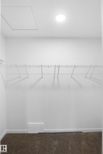 This functional closet features white wire shelving, a ceiling light fixture, and carpeting - Edmonton, AB - Indoor With Storage