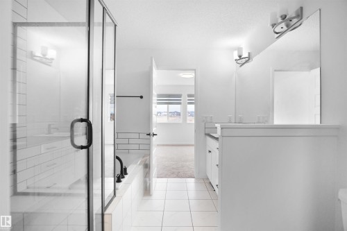 Bathroom featuring a glass-enclosed shower, a separate bathtub, and a double vanity with an expansive mirror - Edmonton, AB - Indoor Photo Showing Bathroom