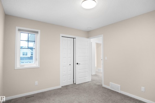 This interior room features neutral tone walls, grey carpeting, a window with white trim, and a white ceiling light fixture - Edmonton, AB - Indoor Photo Showing Other Room