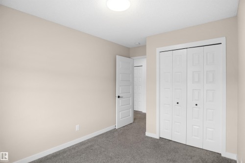 An interior room with neutral-toned walls, grey carpet flooring, and a white ceiling with a flush-mount light fixture - Edmonton, AB - Indoor