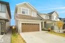 The property presents a pleasing exterior with a two-car garage, concrete driveway, and light-colored siding, complemented by darker accents and a prominent front gable - Edmonton, AB  - Outdoor 