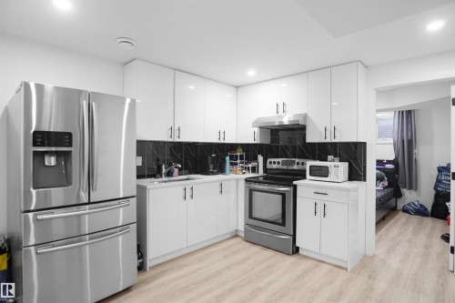 The kitchen features stainless steel appliances, including a French door refrigerator, a range, and an overhead microwave - Edmonton, AB - Indoor Photo Showing Kitchen