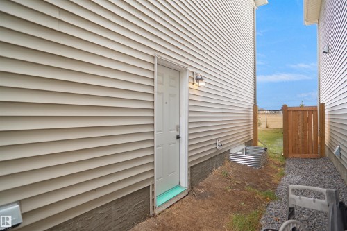 The property features light-colored horizontal siding, a side door with an exterior light fixture, and a window well - Edmonton, AB - Outdoor With Exterior