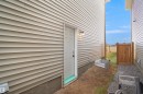 The property features light-colored horizontal siding, a side door with an exterior light fixture, and a window well - Edmonton, AB  - Outdoor With Exterior 