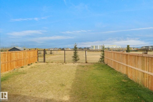 The property includes a backyard with a wooden privacy fence, a partial lawn, and a chain-link fence with a gate - Edmonton, AB - Outdoor