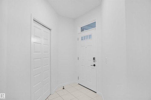 Entryway featuring a white paneled door with glass inserts and an overhead transom window, alongside a white bi-fold closet door - Edmonton, AB - Indoor Photo Showing Other Room