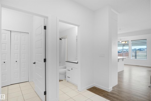 This interior features light-colored tile flooring, white walls, and white paneled doors with dark hardware - Edmonton, AB - Indoor Photo Showing Other Room