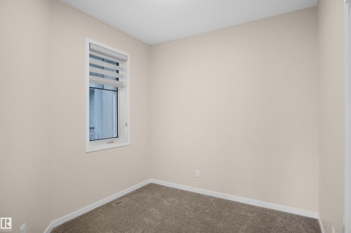 The room features neutral-toned walls, a window with blinds, and carpeted flooring - Edmonton, AB - Indoor Photo Showing Other Room