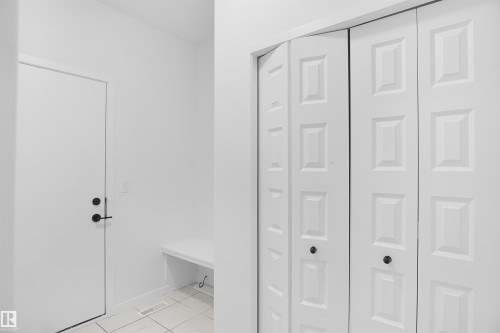 This entryway features a white door with black hardware, a built-in white bench, and bifold closet doors - Edmonton, AB - Indoor Photo Showing Other Room