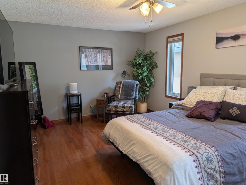 The property features hardwood floors, light gray walls, and a ceiling fan with integrated lighting - 65 Coloniale Way, Beaumont, AB - Indoor Photo Showing Bedroom