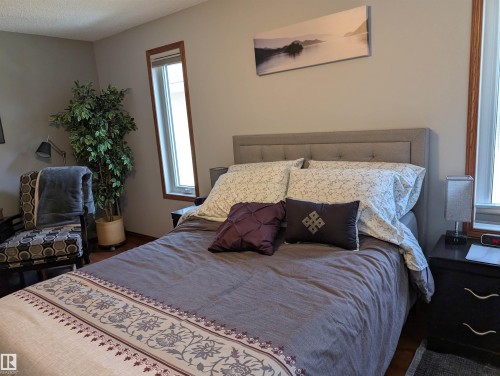 This property features light gray walls and wood flooring - 65 Coloniale Way, Beaumont, AB - Indoor Photo Showing Bedroom
