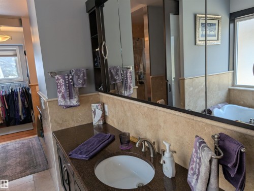 Bathroom featuring a vanity with a dark granite countertop and a built-in sink - 65 Coloniale Way, Beaumont, AB - Indoor Photo Showing Bathroom