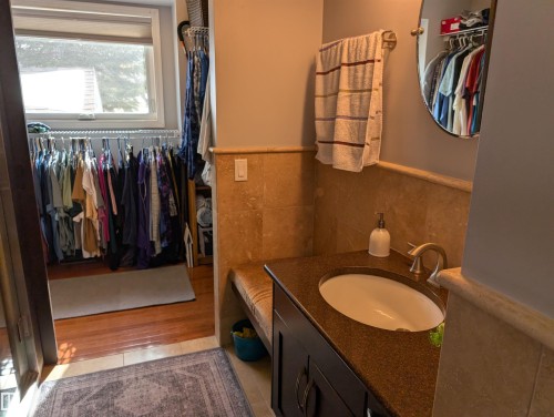 The bathroom features a vanity with an undermount sink, a dark countertop, and brushed nickel fixtures - 65 Coloniale Way, Beaumont, AB - Indoor Photo Showing Bathroom
