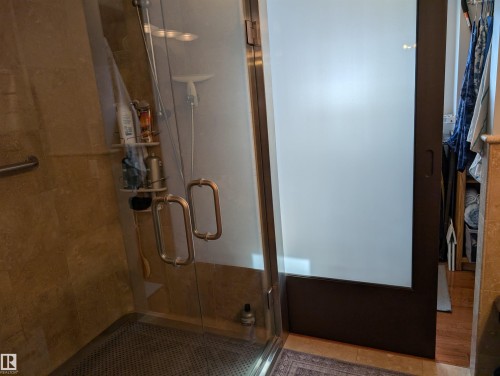 The shower features clear glass doors with bronze handles, and a tiled interior with a grab bar - 65 Coloniale Way, Beaumont, AB - Indoor Photo Showing Other Room