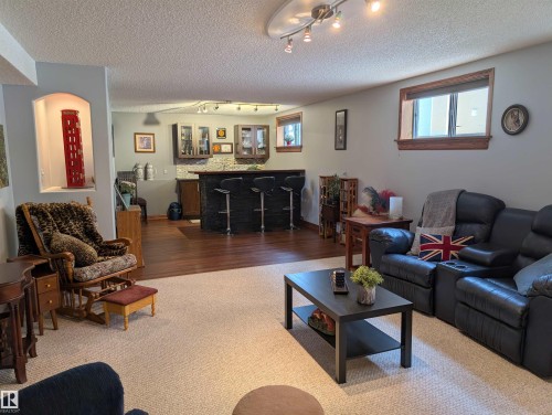 Expansive living area featuring light-colored carpeting, recessed lighting, and a distinct bar area with dark wood flooring - 65 Coloniale Way, Beaumont, AB - Indoor Photo Showing Living Room