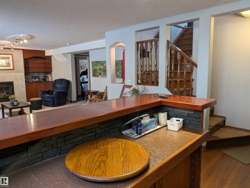 This property features a well-appointed bar area with a stone-look finish and a wooden countertop - 65 Coloniale Way, Beaumont, AB - Indoor With Fireplace