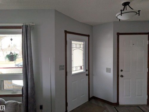 Entryway featuring a white door with decorative glass, a second white door, and a flush mount ceiling light fixture - 65 Coloniale Way, Beaumont, AB - Indoor Photo Showing Other Room