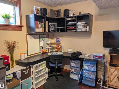 This room features warm-toned walls, a window with a wood trim, and built-in wall-mounted shelving providing storage - 65 Coloniale Way, Beaumont, AB - Indoor Photo Showing Office