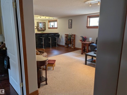 Spacious room featuring a bar area with dark cabinetry and a wood countertop, hardwood flooring, and light-colored carpeting - 65 Coloniale Way, Beaumont, AB - Indoor Photo Showing Other Room