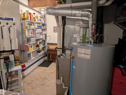 This utility area features a water heater, furnace, and exposed ceiling joists - 65 Coloniale Way, Beaumont, AB - Indoor Photo Showing Basement