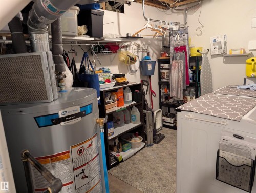 Utility area featuring a water heater, shelving, and a washing machine - 65 Coloniale Way, Beaumont, AB - Indoor Photo Showing Basement