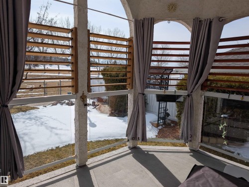 The property features an enclosed patio area with floor-to-ceiling windows, louvered wooden panels, and privacy curtains - 65 Coloniale Way, Beaumont, AB - Indoor Photo Showing Other Room