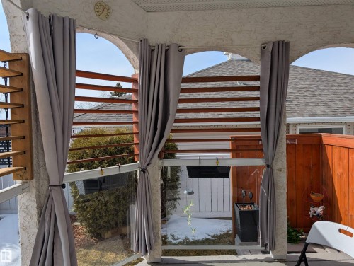 The property features a screened-in porch with arched openings, privacy curtains, and a wooden slat privacy screen - 65 Coloniale Way, Beaumont, AB - Indoor Photo Showing Other Room