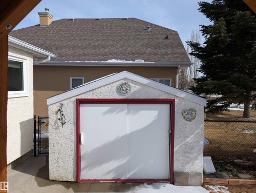 The property includes a detached storage shed with a white exterior, red trim, and a white door - 65 Coloniale Way, Beaumont, AB - Outdoor With Exterior