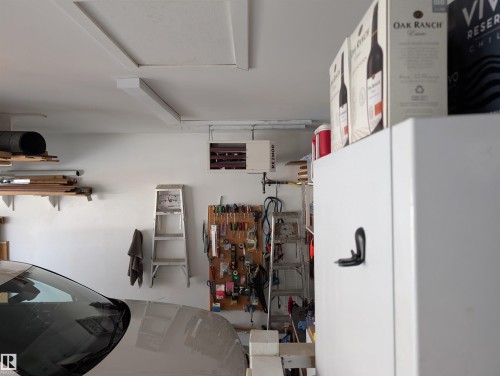 The garage features a white painted ceiling and walls, with visible overhead lighting - 65 Coloniale Way, Beaumont, AB - Indoor