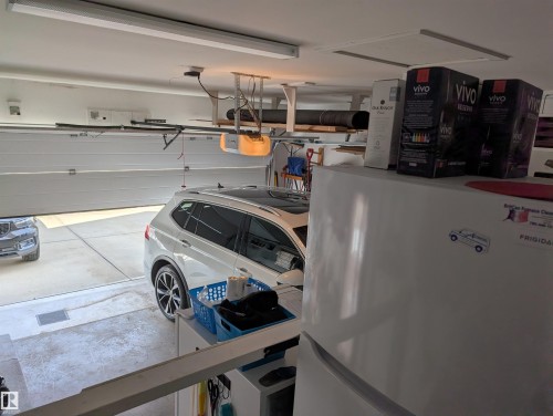 The property features an attached garage with a white garage door, an automatic garage door opener, and concrete flooring - 65 Coloniale Way, Beaumont, AB - Indoor Photo Showing Garage
