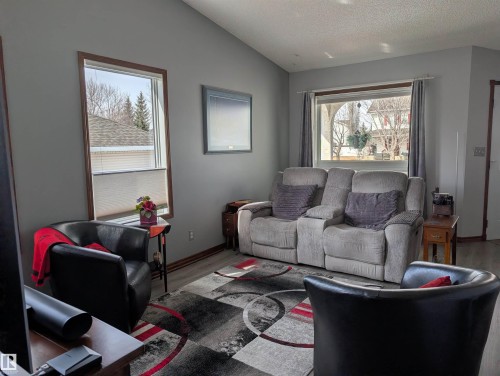 Living area featuring light grey walls, sloped ceilings, and wood-trimmed windows - 65 Coloniale Way, Beaumont, AB - Indoor Photo Showing Living Room