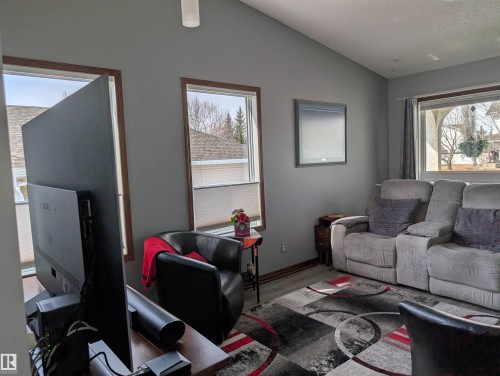 This inviting living area features light gray walls, a sloped ceiling, and wood-trimmed windows providing natural light - 65 Coloniale Way, Beaumont, AB - Indoor Photo Showing Living Room