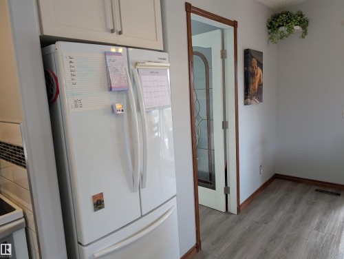 This kitchen features white cabinetry and a white refrigerator - 65 Coloniale Way, Beaumont, AB - Indoor