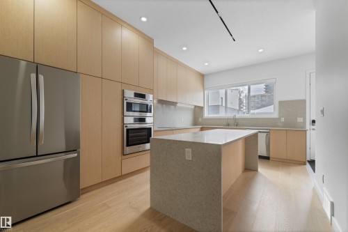 Contemporary kitchen with light wood cabinetry, stainless steel appliances, a center island with a light-colored countertop, and recessed lighting - 14037 104 Avenue, Edmonton, AB - Indoor Photo Showing Kitchen