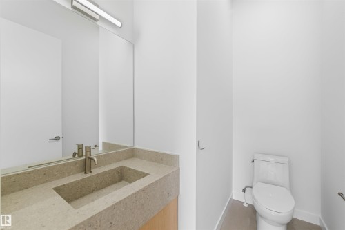The bathroom features a modern vanity with an integrated sink and a sleek faucet, complemented by a large mirror with overhead lighting - 14037 104 Avenue, Edmonton, AB - Indoor Photo Showing Bathroom