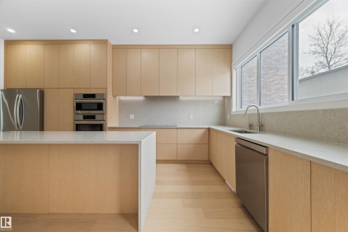This kitchen features light wood cabinetry, stainless steel appliances, and light-colored countertops - 14037 104 Avenue, Edmonton, AB - Indoor Photo Showing Kitchen With Upgraded Kitchen