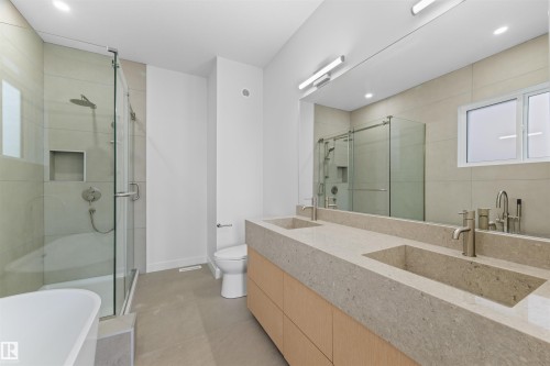 The bathroom features a modern vanity with dual integrated sinks, brushed nickel faucets, and a large mirror - 14037 104 Avenue, Edmonton, AB - Indoor Photo Showing Bathroom