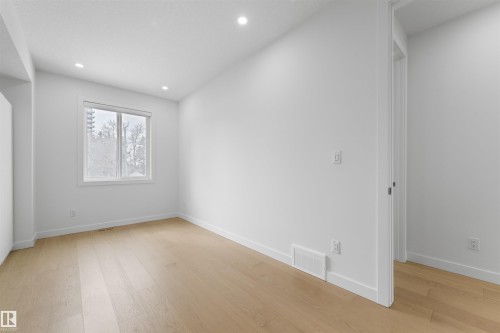This room features light hardwood flooring, recessed lighting, and a window with a view of trees - 14037 104 Avenue, Edmonton, AB - Indoor Photo Showing Other Room