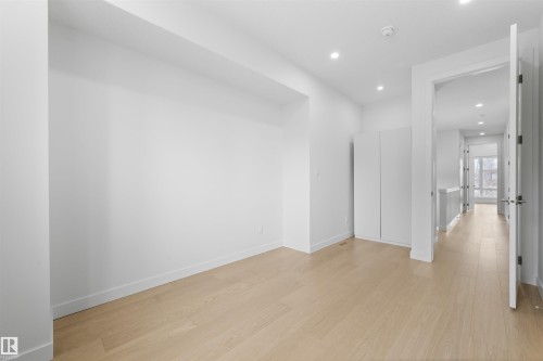 This bright space features light-toned hardwood flooring and recessed lighting, offering a versatile area - 14037 104 Avenue, Edmonton, AB - Indoor Photo Showing Other Room